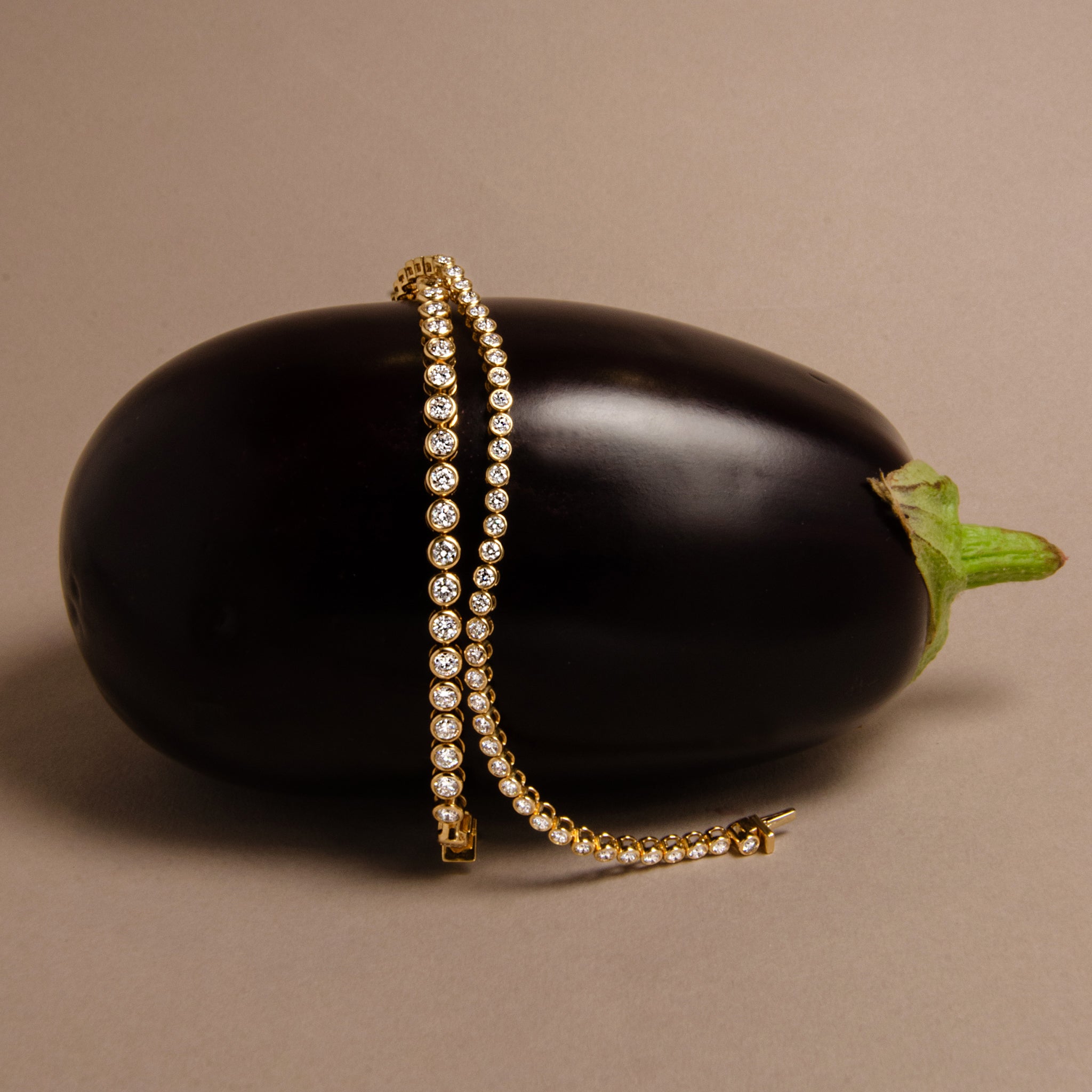 Two gold tennis bracelets with round bezel set diamonds