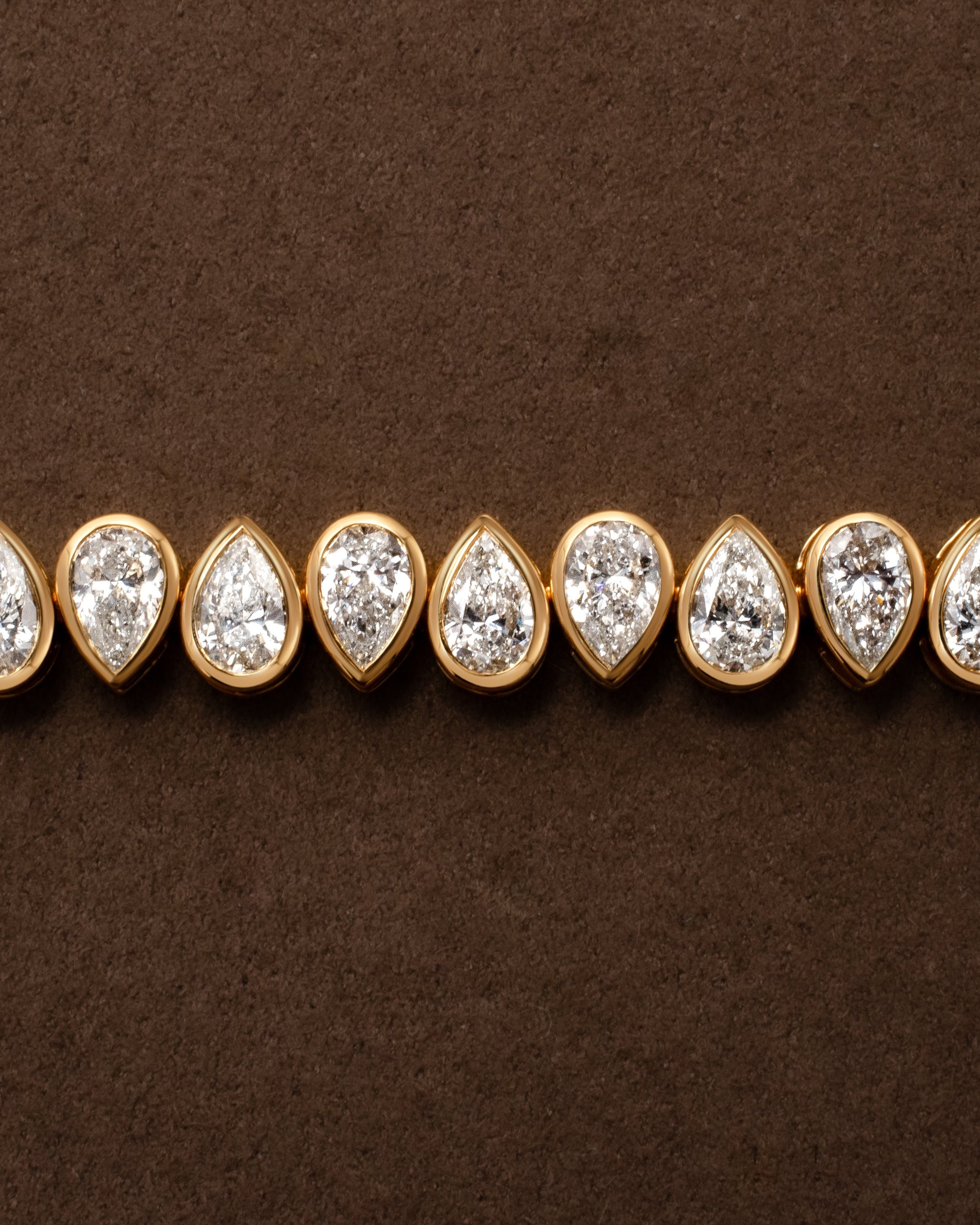 Gold tennis bracelet with bezel set pear shaped diamonds