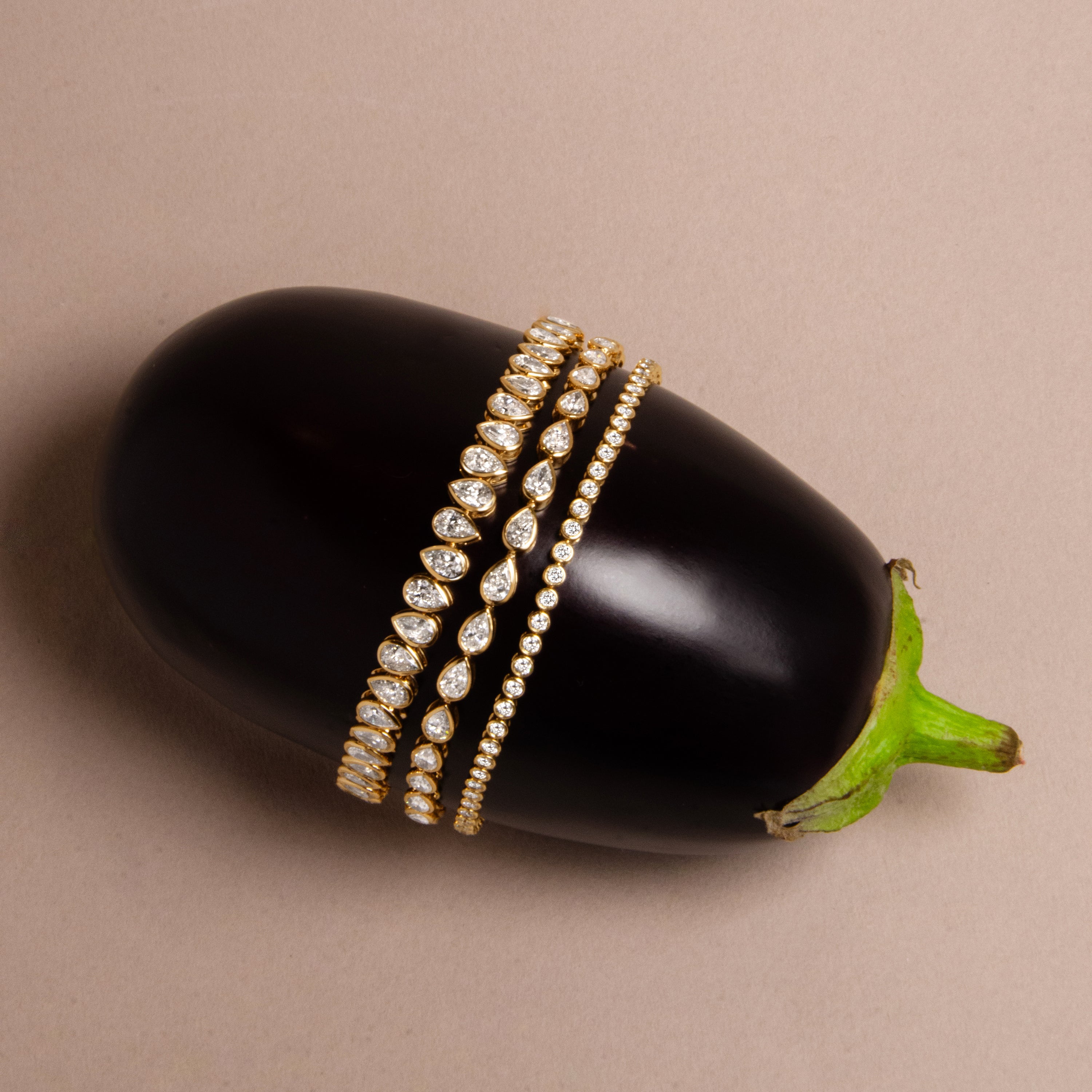 Three bezel set yellow gold tennis bracelets with pear and round shaped diamonds