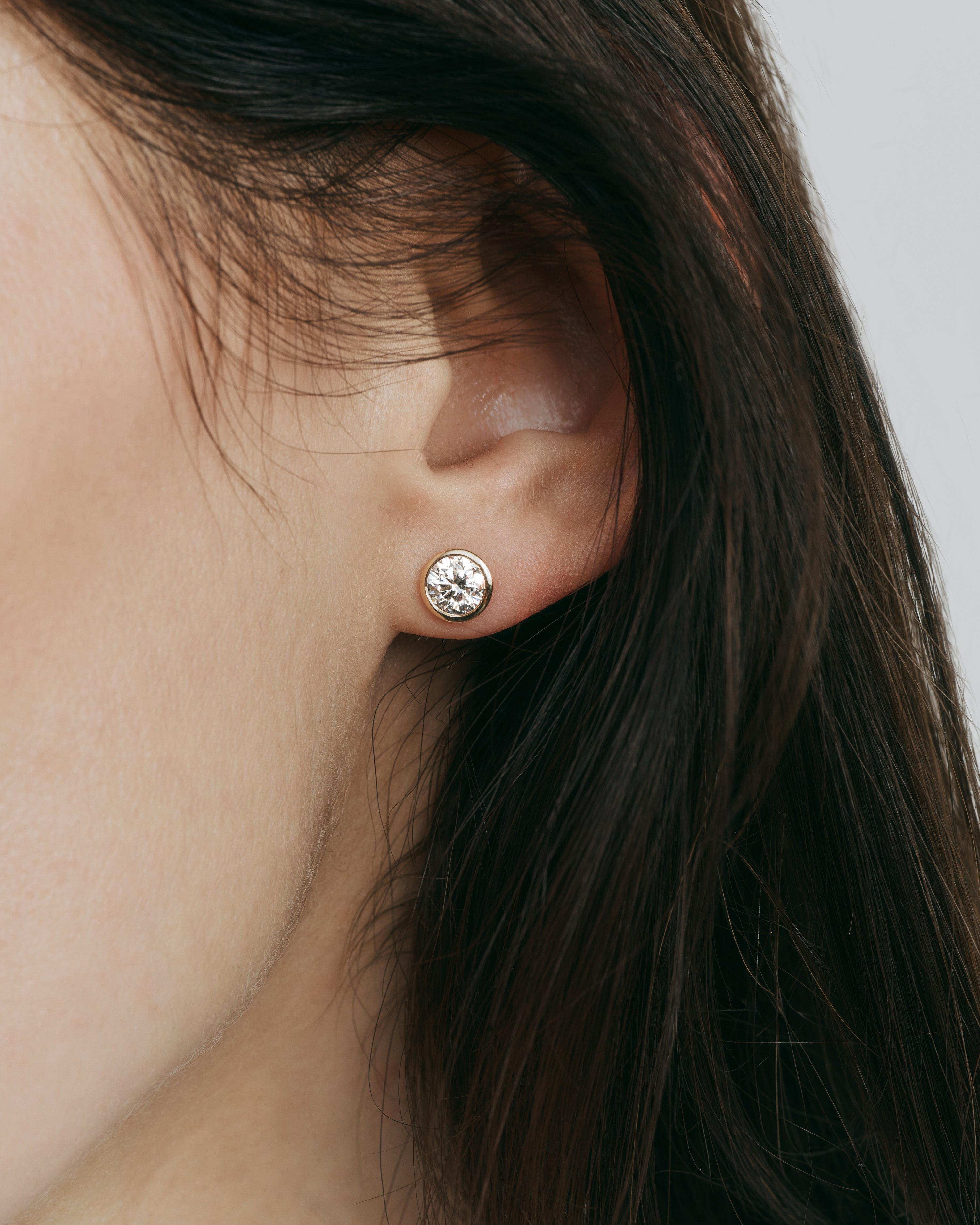 yellow gold bezel set earring stud with round brilliant diamond