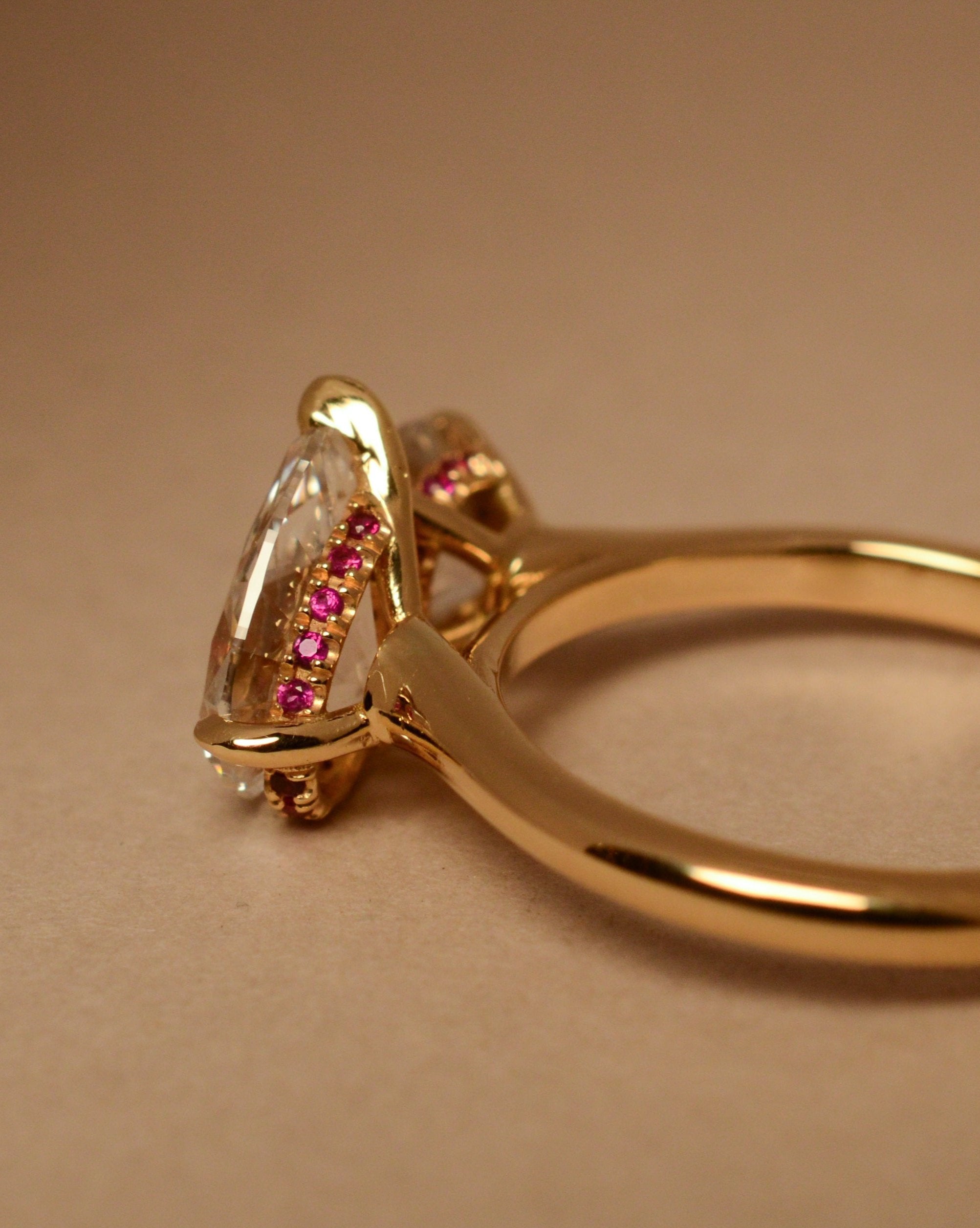 yellow gold two stone engagement ring with round and pear diamond and red ruby pave