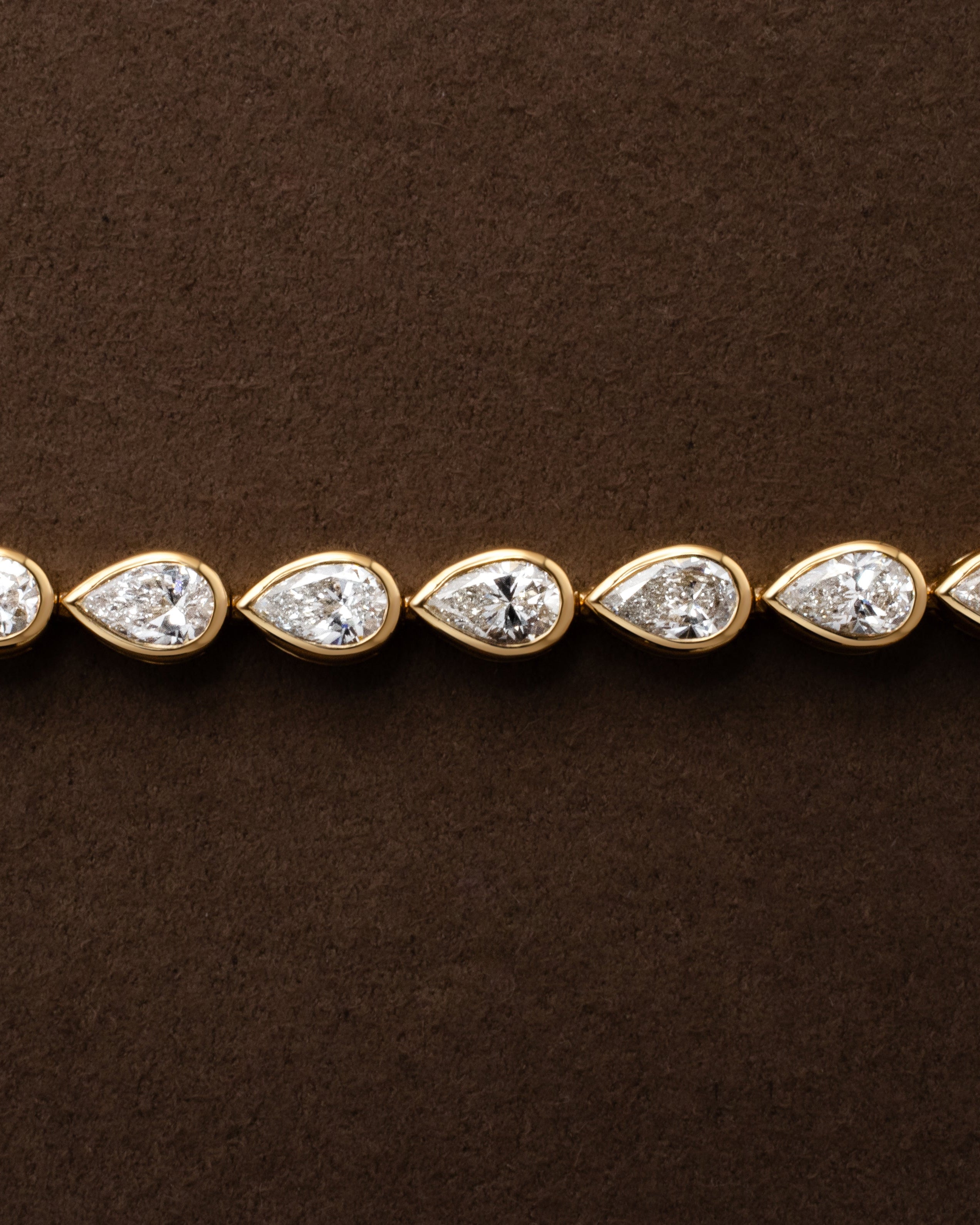gold tennis bracelet with pear shaped bezel set diamonds