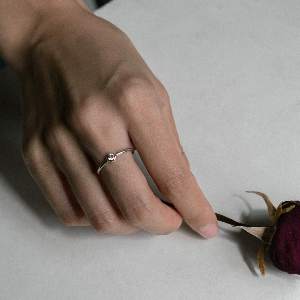 clean silver ring with bezel set diamond on a rose